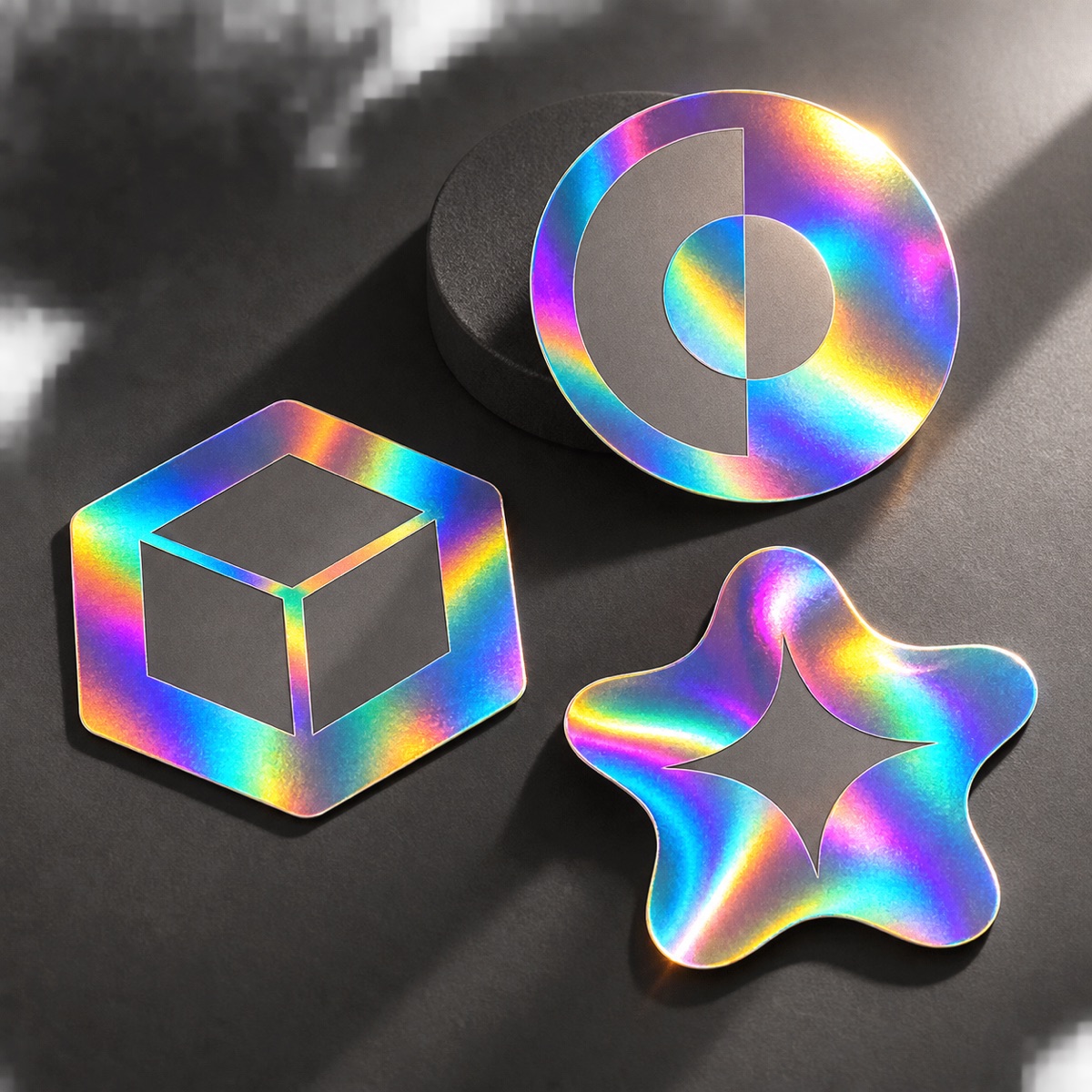 Three holographic sticker label shapes throwing rainbow iridescent highlights